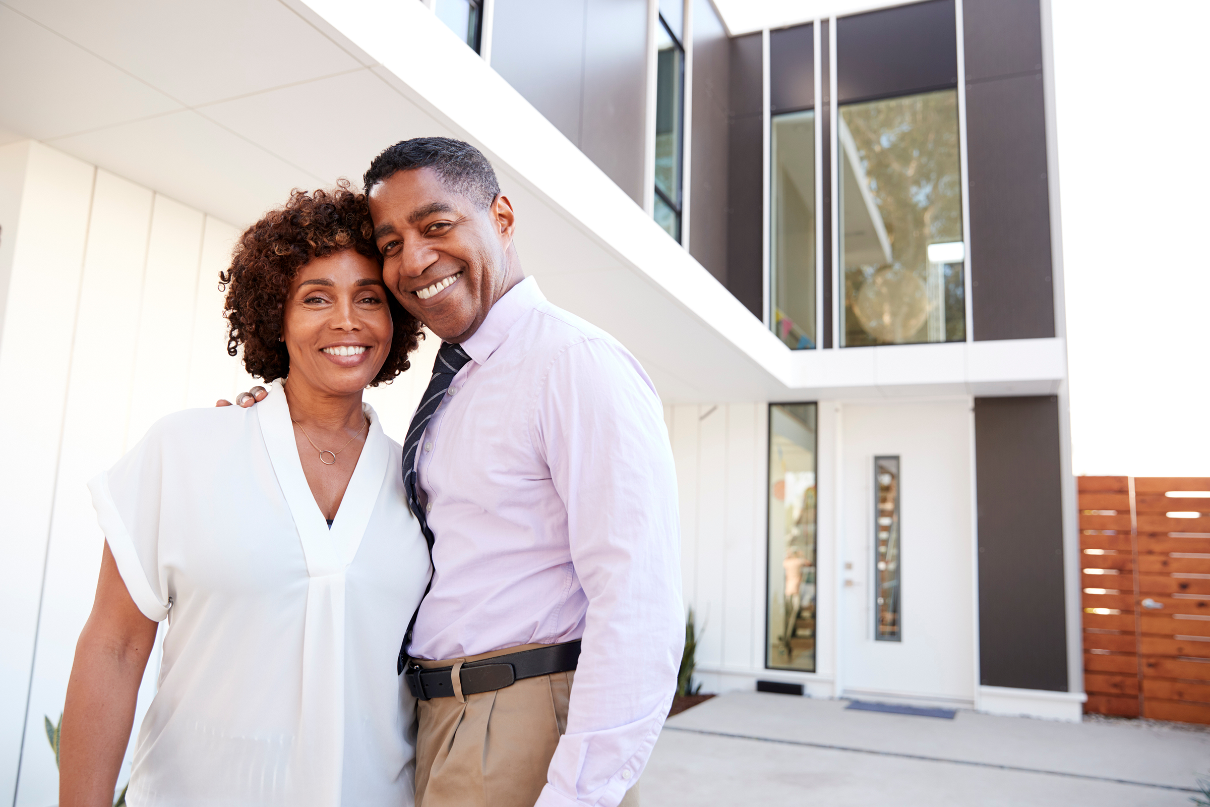 Happy couple standing outside of their home.